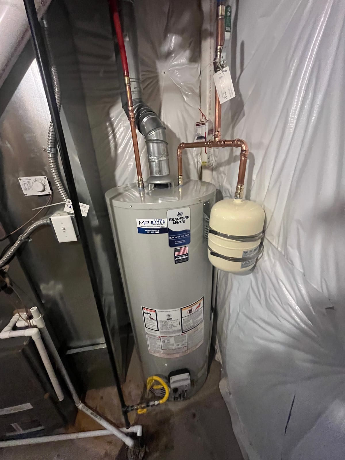 Installed gas water heater with copper piping, expansion tank, and Mayer Plumbing label